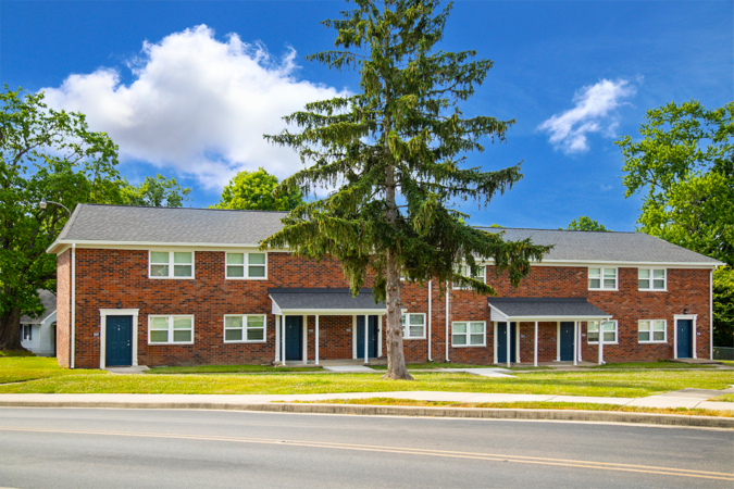 Brick apartment building with a large tree in the front yard