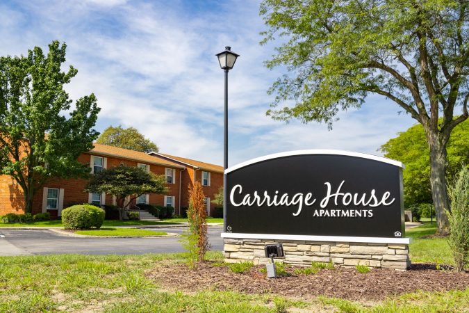 Landscaped area with Carriage House Apartments sign